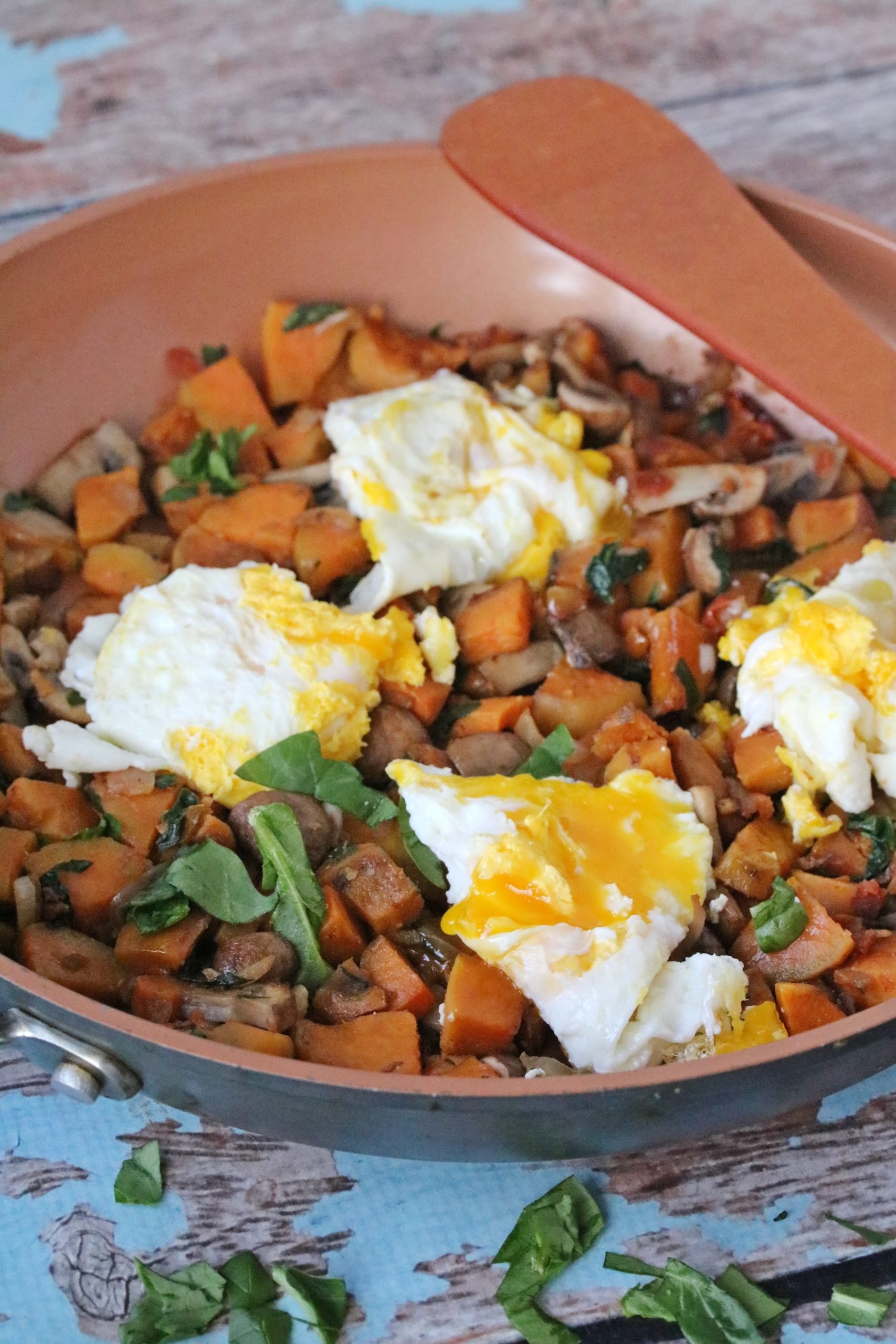 Breakfast sweet potato hash in a pan topped with eggs