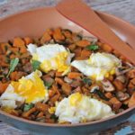 Breakfast sweet potato hash in a pan topped with eggs