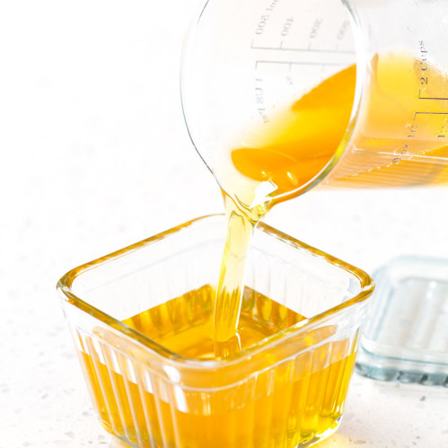 pouring melted homemade ghee into a glass butter dish
