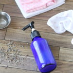 Diy face wash in a blue bottle with wash cloths and lavender behind it