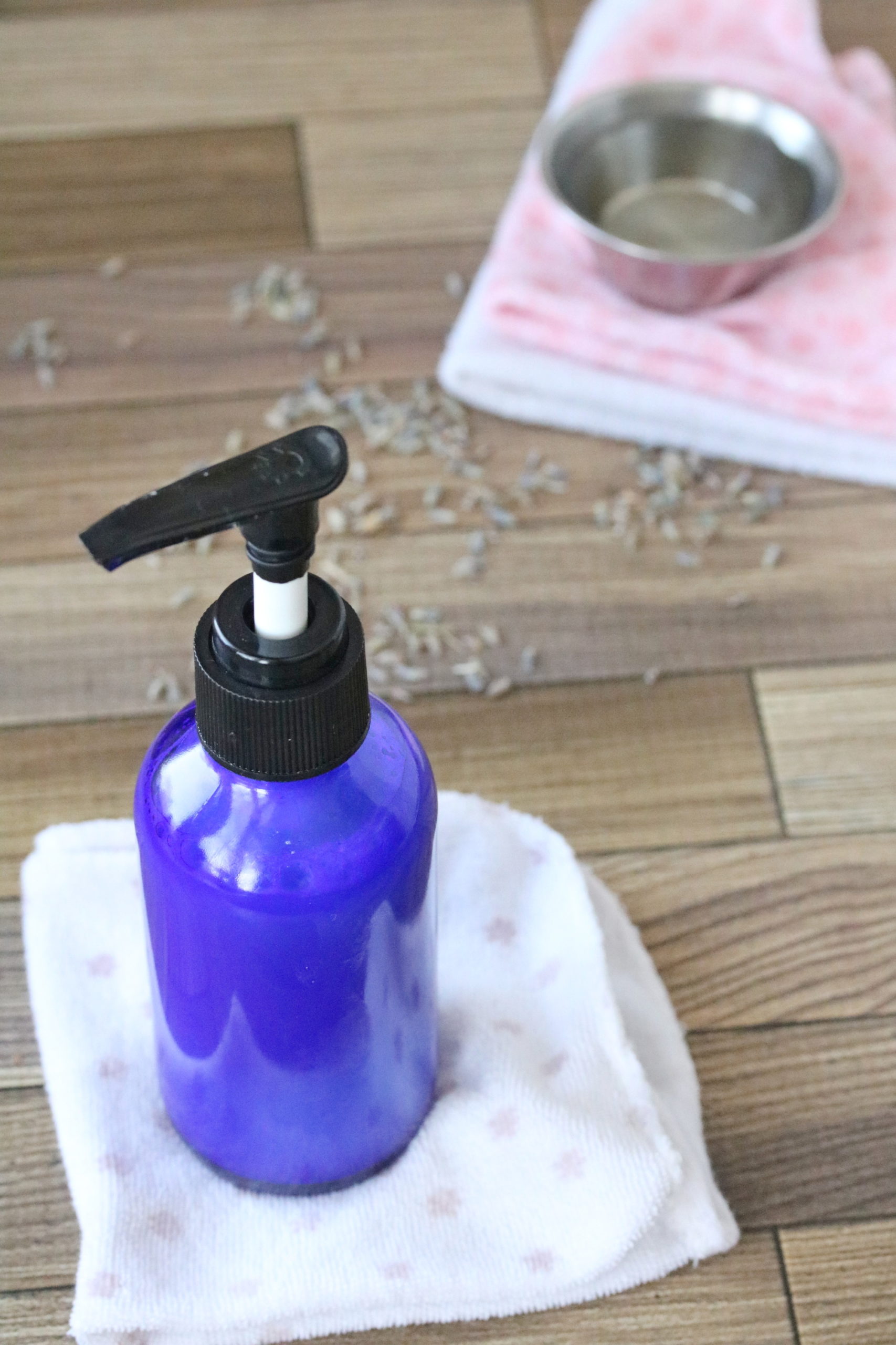 Diy face wash in a blue bottle with wash cloths and lavender behind it